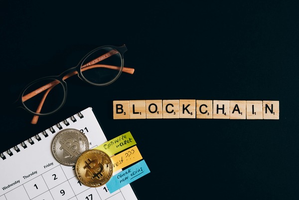 Blockchain letter tiles next to crypto coins and review notes