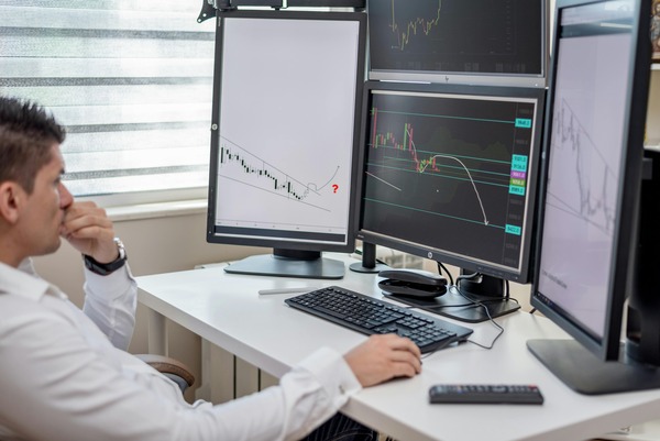 Support specialist monitoring exchange charts on several screens