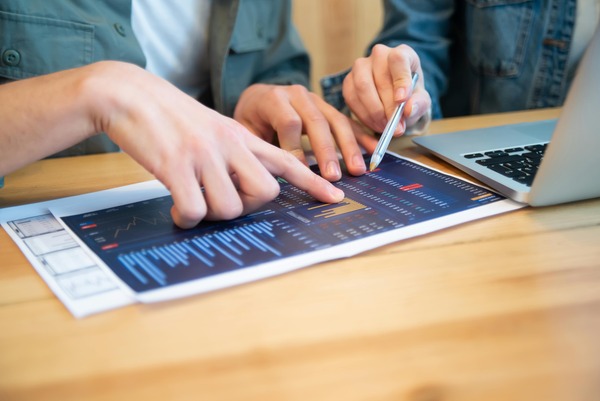 People reviewing printed crypto market charts on a desk