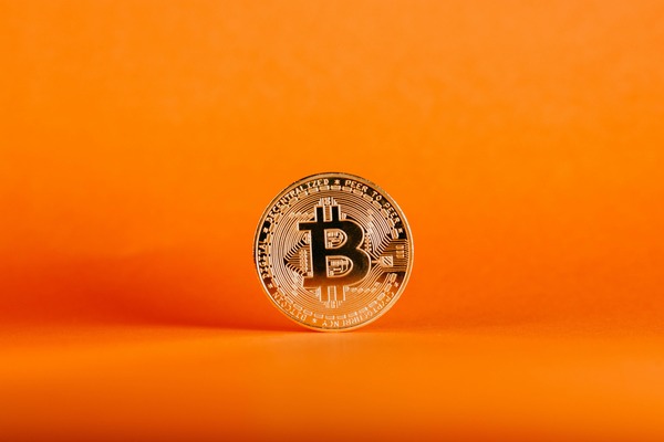 Gold crypto coin standing on an orange background